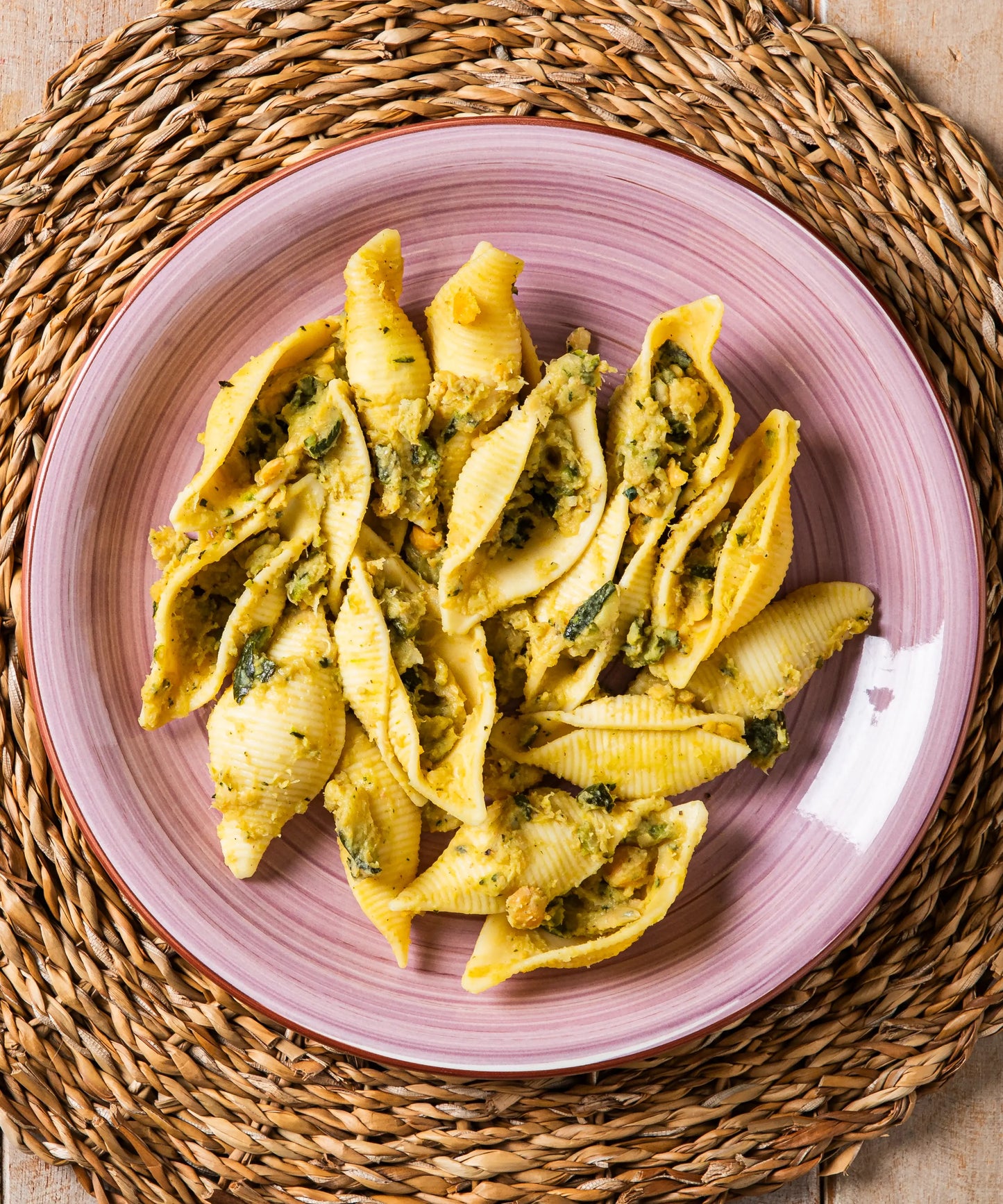 Una piatto di conchiglioni al pesto di zucchine e ceci con gusto delicato servito su piatto rosa in ceramica
