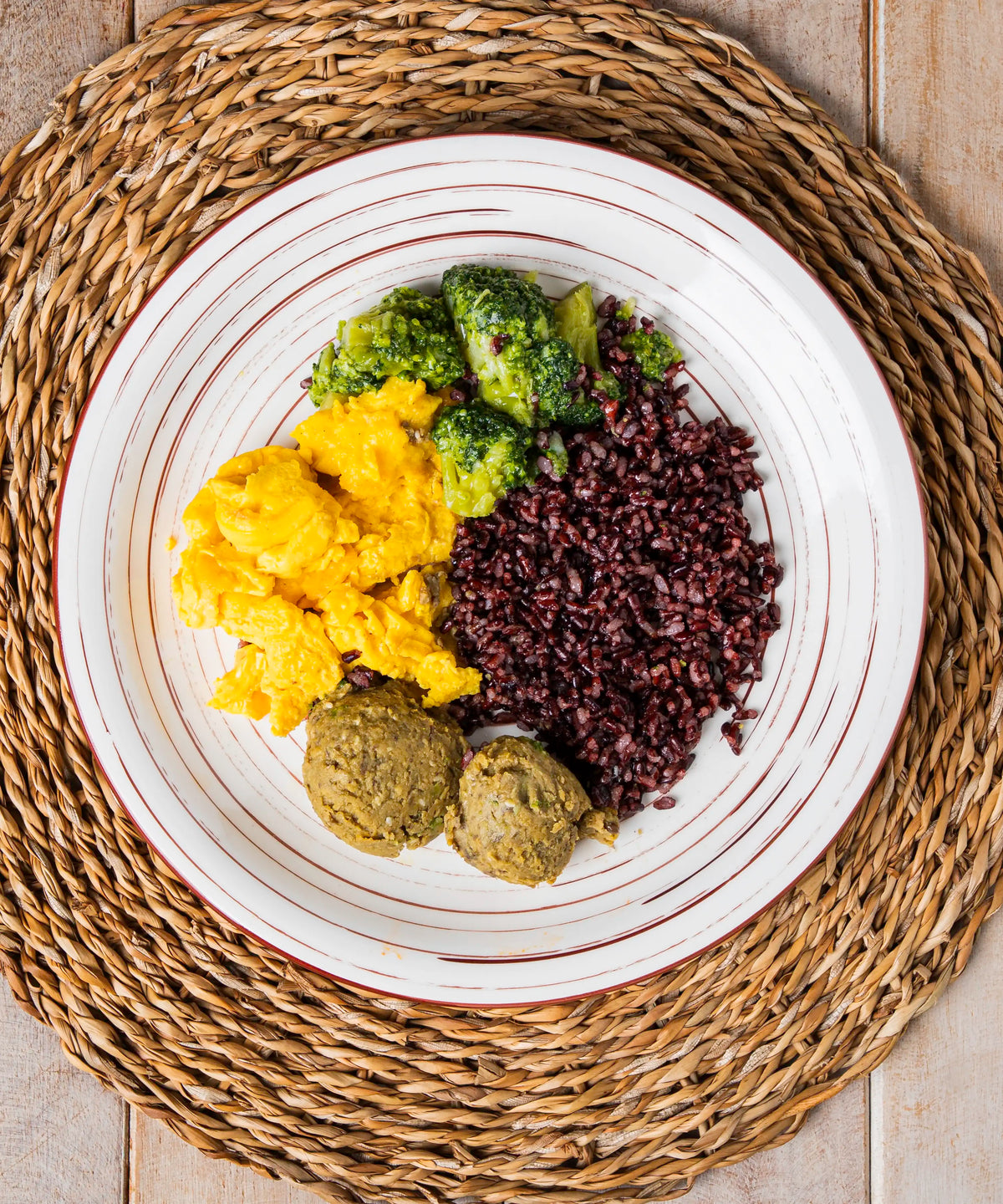 Nutri bowl con riso nero integrale, uova strapazzate, broccoli e lenticchie in ciotola di ceramica bianca a strisce marroni