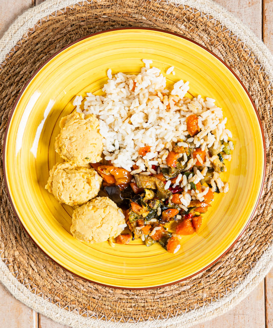 Bowl mediterranea equilibrata con riso basmati, hummus e verdurine servita su piatto in ceramica giallo con bordo marrone