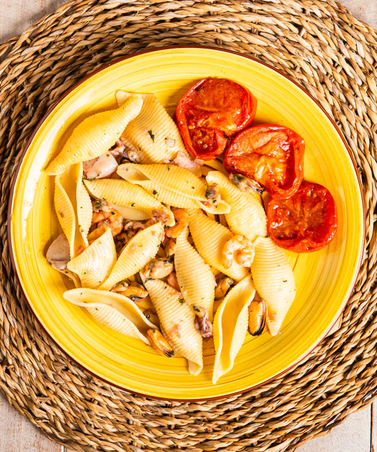 Piatto giallo in ceramica con conchiglioni ai frutti di mare pomodori ideale con salsiccia lenticchie o zuppa