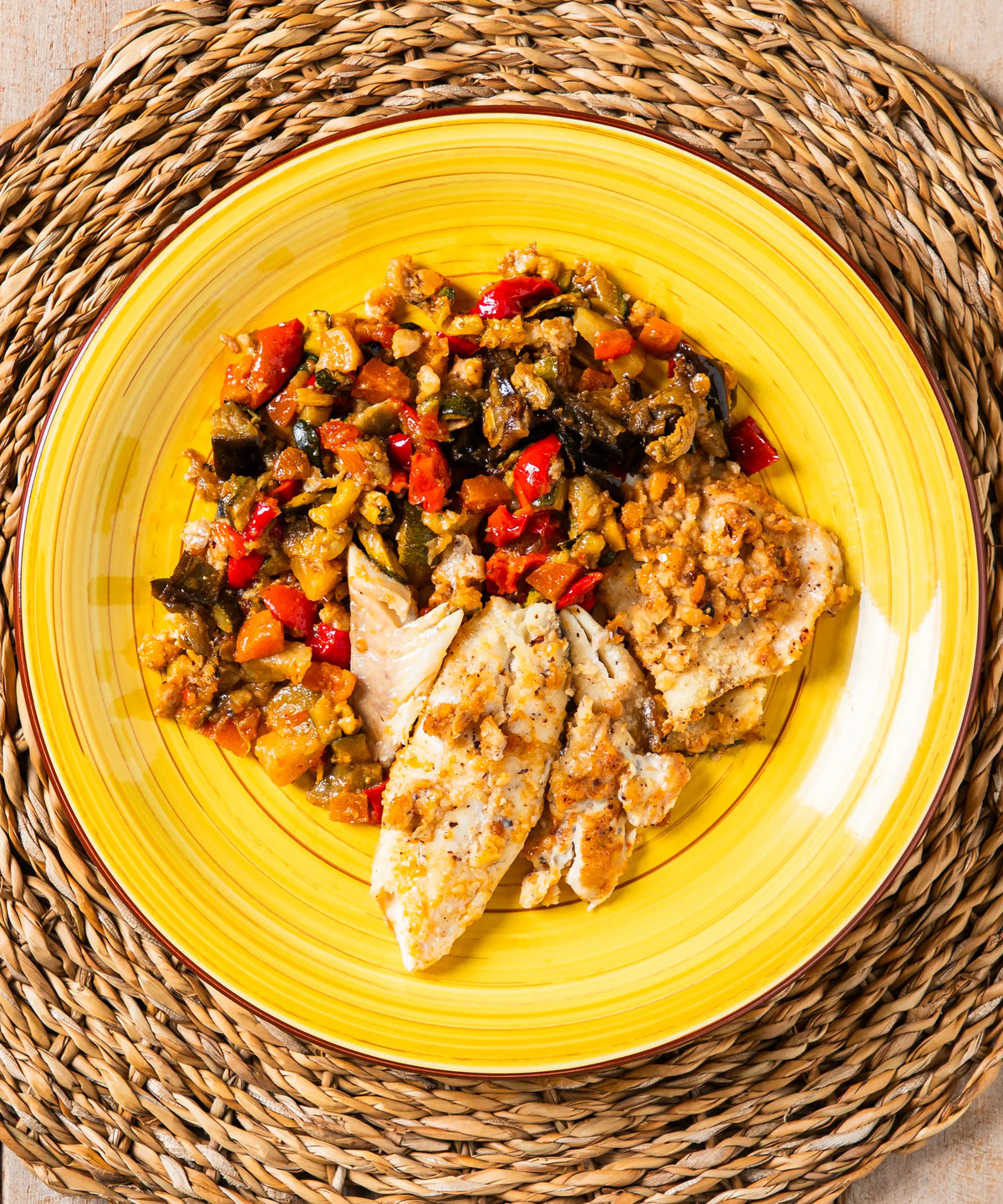 Piatto giallo ceramica con filetto di merluzzo alle nocciole del piemonte e verdurine in umido
