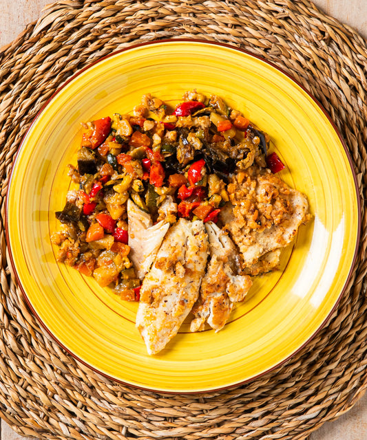 Piatto giallo ceramica con filetto di merluzzo alle nocciole del piemonte e verdurine in umido
