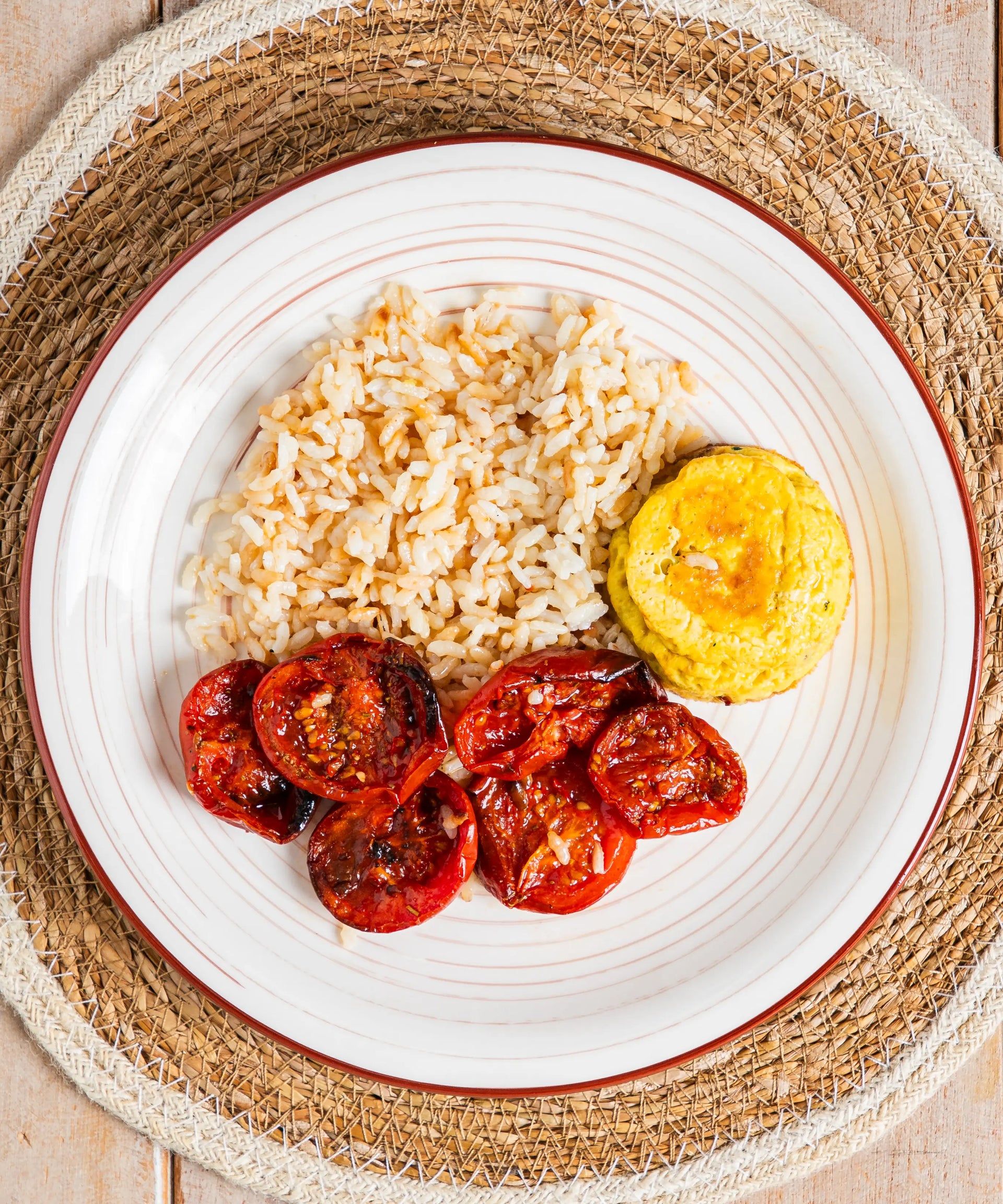 Piatto in ceramica bianca con bordo rosso contenente frittatina alle verdure con riso e pomodorini arrosto