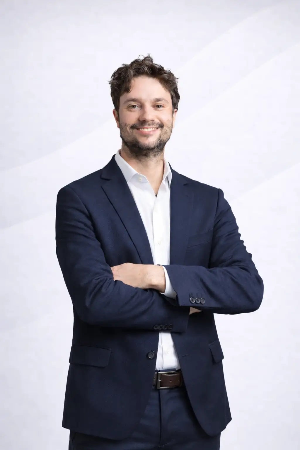 Uomo con giacca blu navy sopra una camicia bianca con le braccia conserte