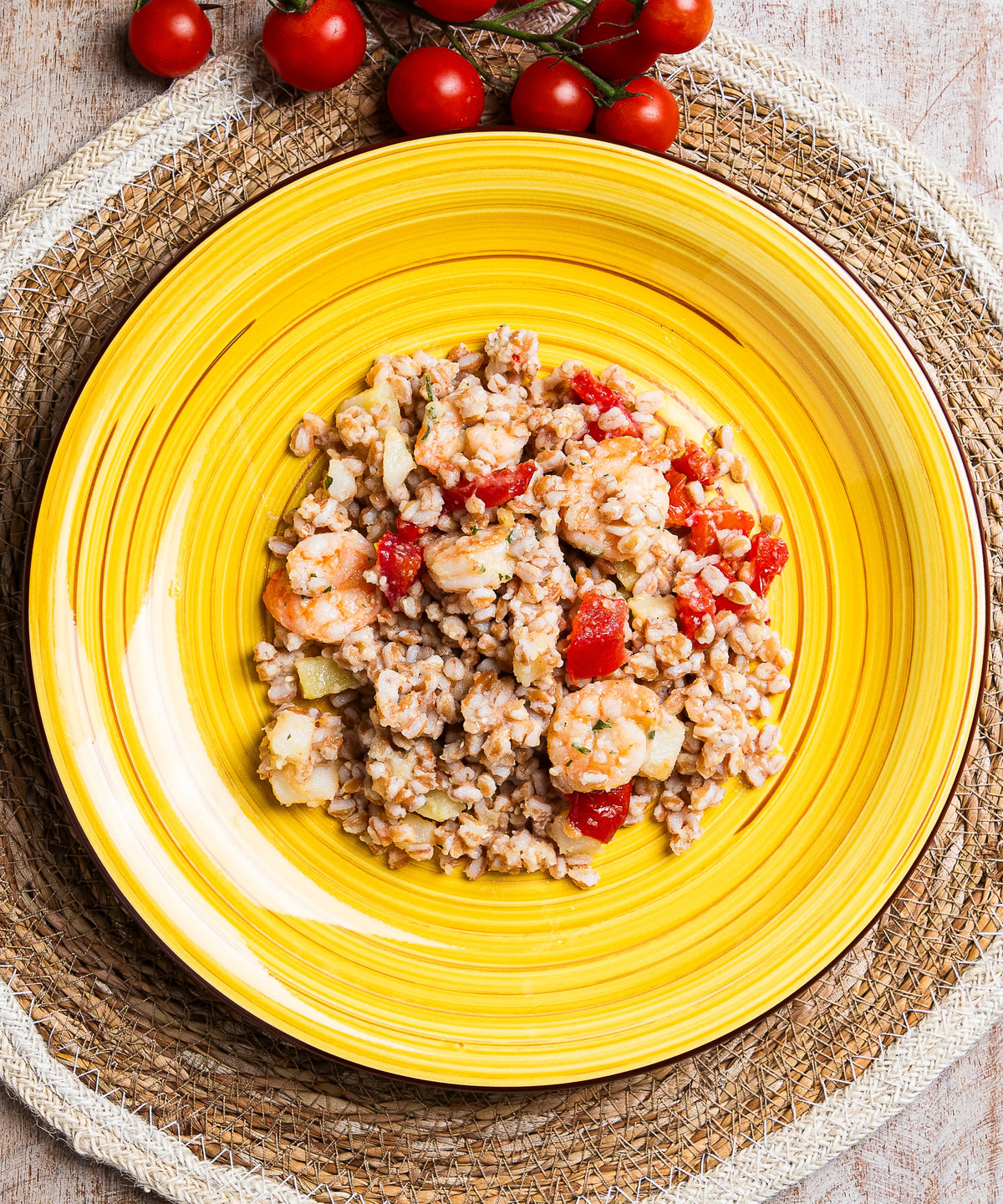 Piatto ceramica giallo vibrante con insalata di farro gamberi patate e pomodorini con design a coste concentriche