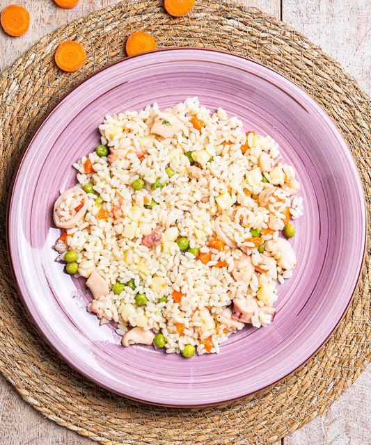 Una vivace insalata di riso al profumo di mare con polpo gamberi e seppie servita su un piatto ceramico viola con scanalature concentriche