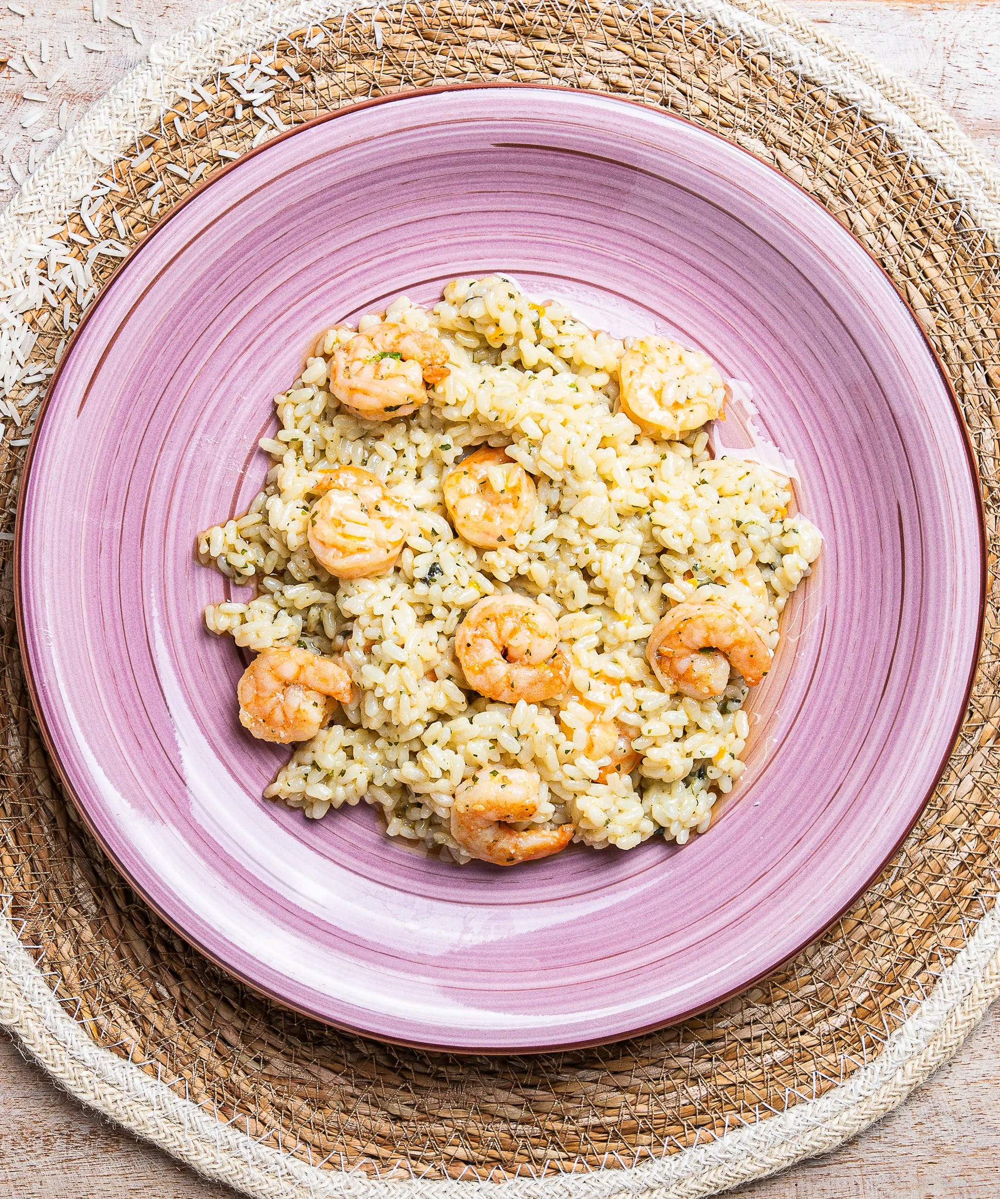 Risotto al mojito con gamberi e zucchine servito su un piatto di ceramica rosa con scanalature concentriche