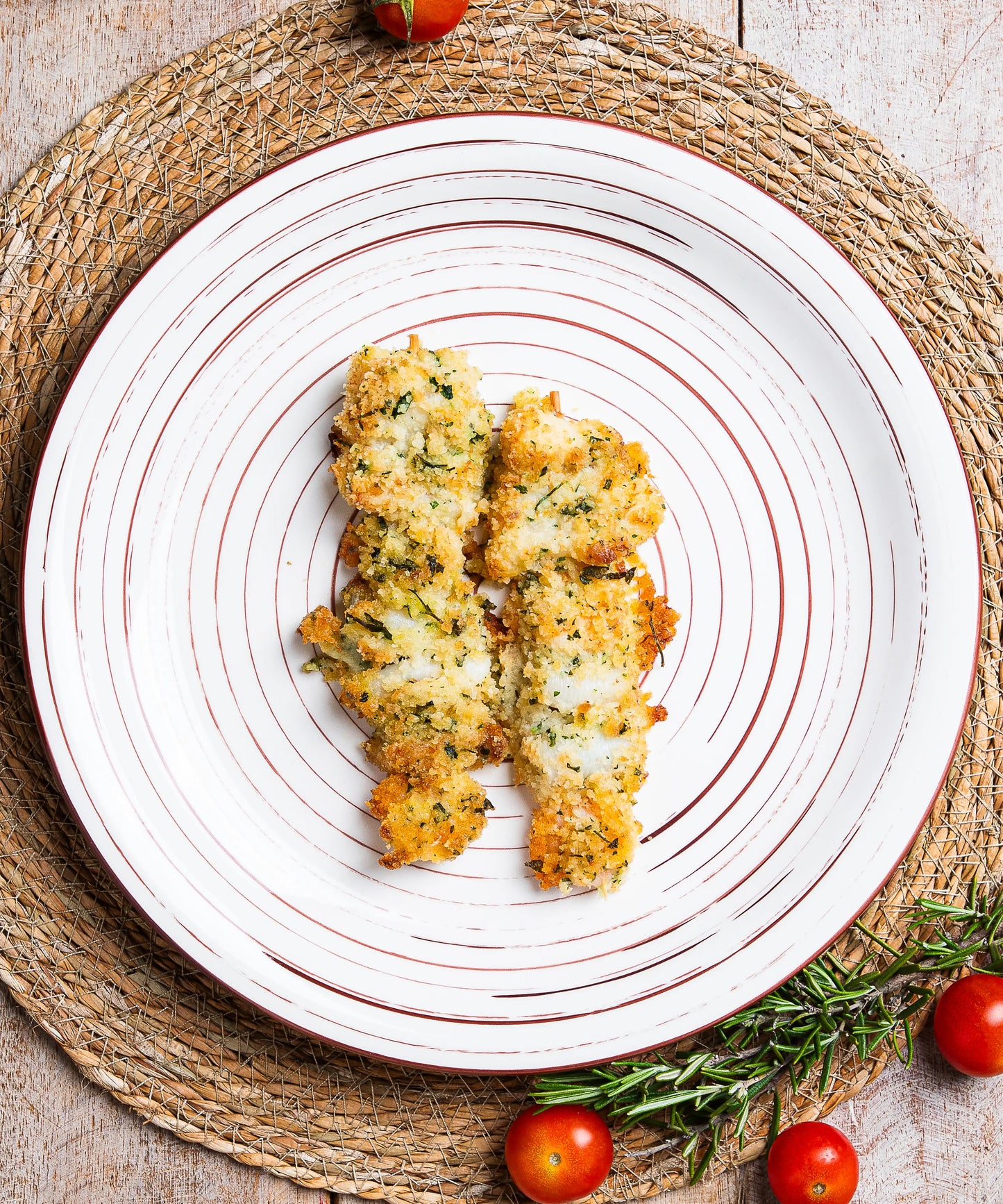 Crispy herb-crusted spiedini misti fish fillets served on a white plate with concentric brown lines