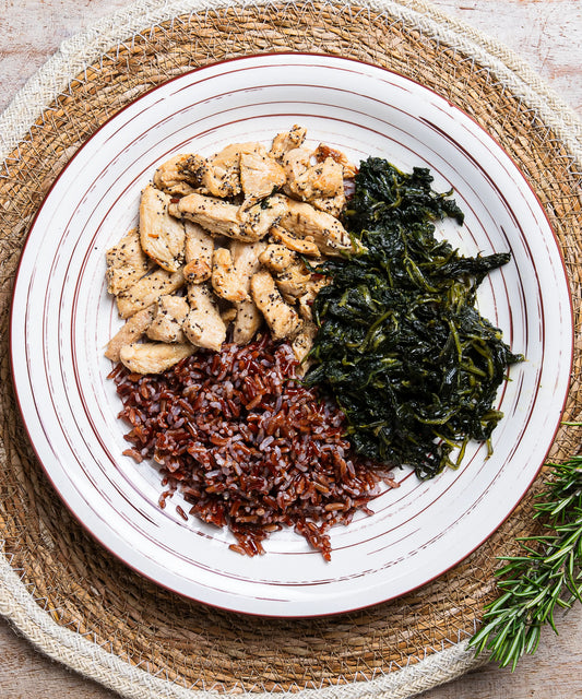Piatto bianco in ceramica con straccetti di pollo al papavero, cicoria e riso rosso integrale rosso integrale