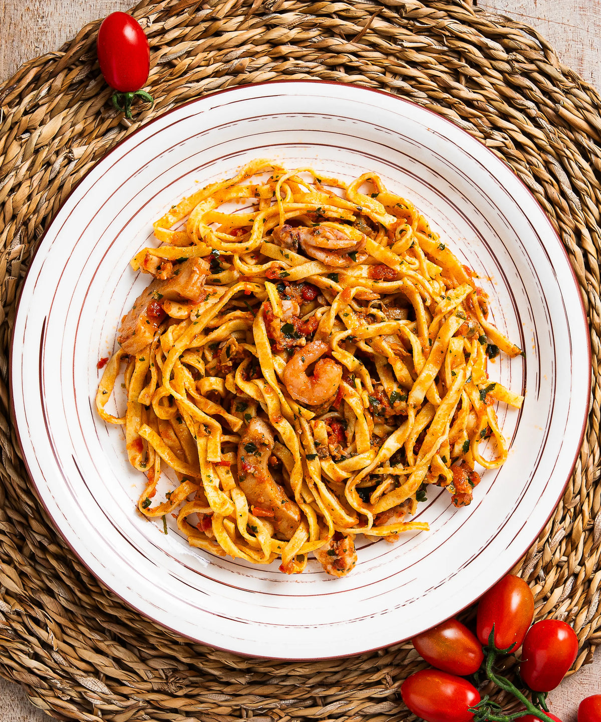 Un piatto di tagliatelle del pescatore allo scoglio con pasta larga gialla e gamberi in salsa di pomodoro ricca